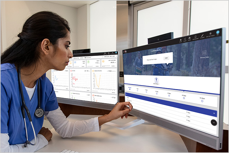 Clinician in scrubs consulting a computer.